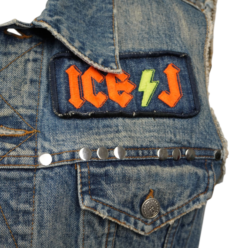 Primo piano della patch ricamata ICE-J con fulmine e della fila di borchie metalliche quadrate applicate sopra il taschino.
