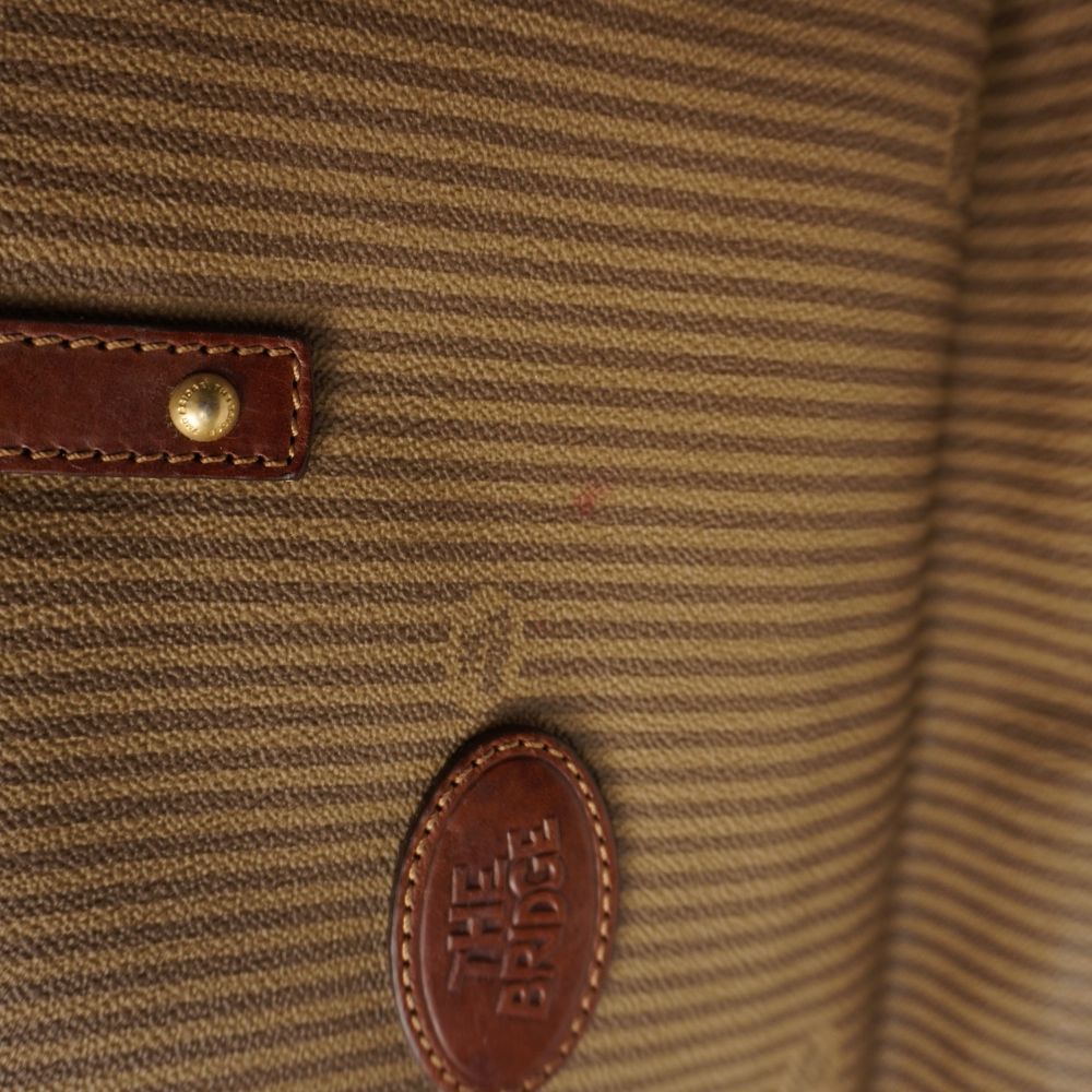 Dettaglio macro del bordo superiore in pelle cuoio e interno sfoderato in tessuto jacquard di borsa The Bridge