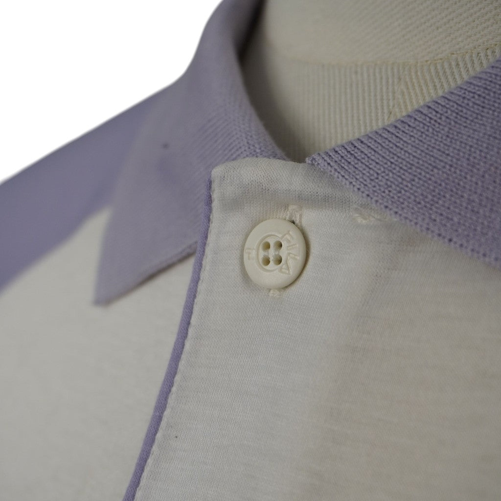 Primo piano del colletto a coste lilla e della patta bottoni bianca di una polo vintage Fila, con focus sul bottone originale con la scritta del brand incisa sul bordo.
