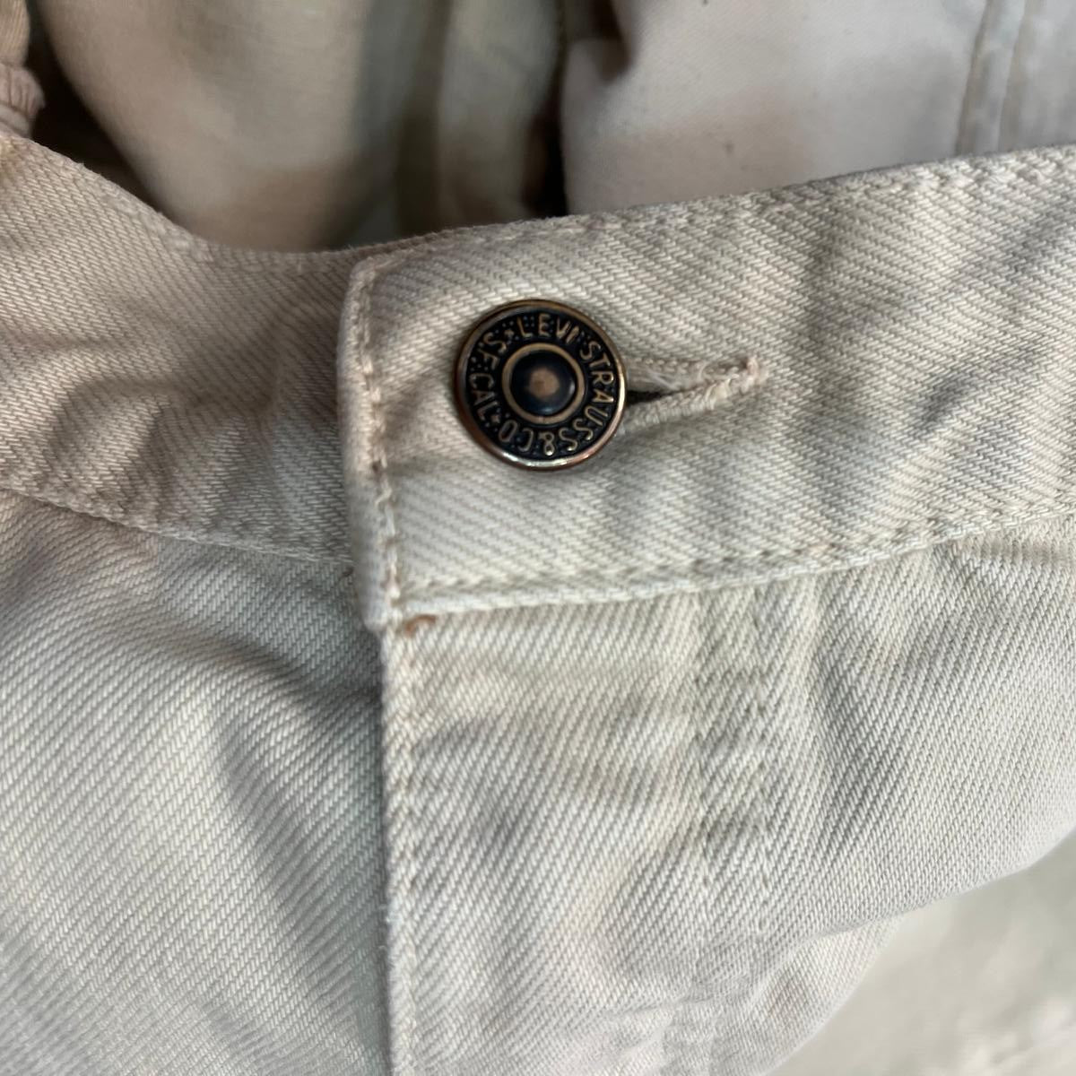 Macro del bottone metallico centrale di chiusura dei jeans con il marchio Levi's Strauss impresso a rilievo.