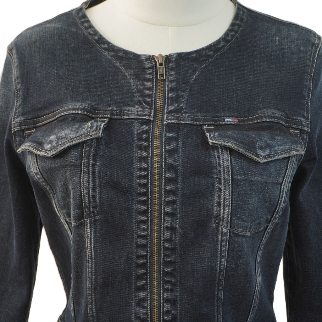 Primo piano del busto della giacca in denim scuro sul manichino, con focus sulle pattine delle tasche pettorali e sui dettagli delle cuciture verticali.
