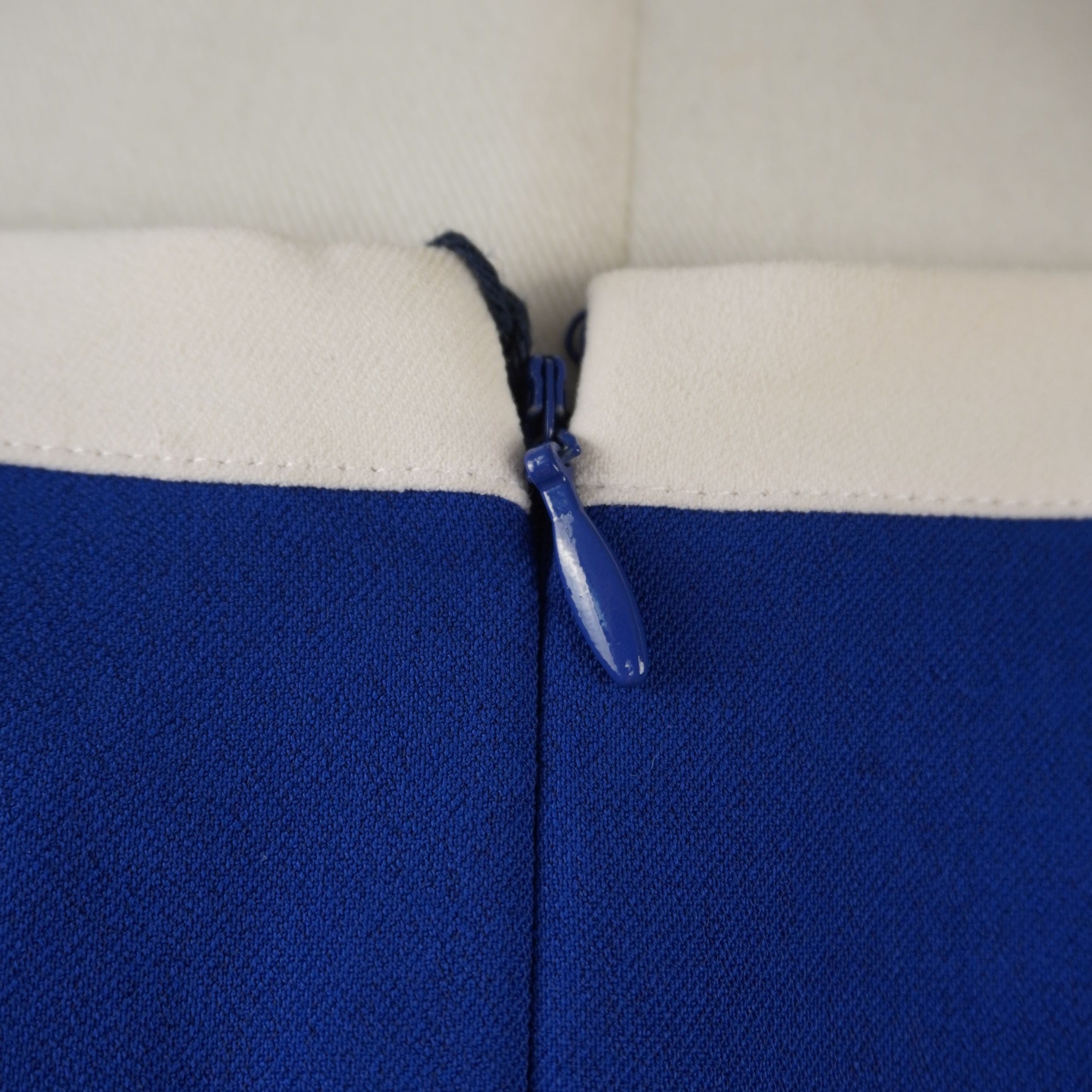 Primo piano della chiusura con zip posteriore invisibile in tinta blu e cursore a goccia.