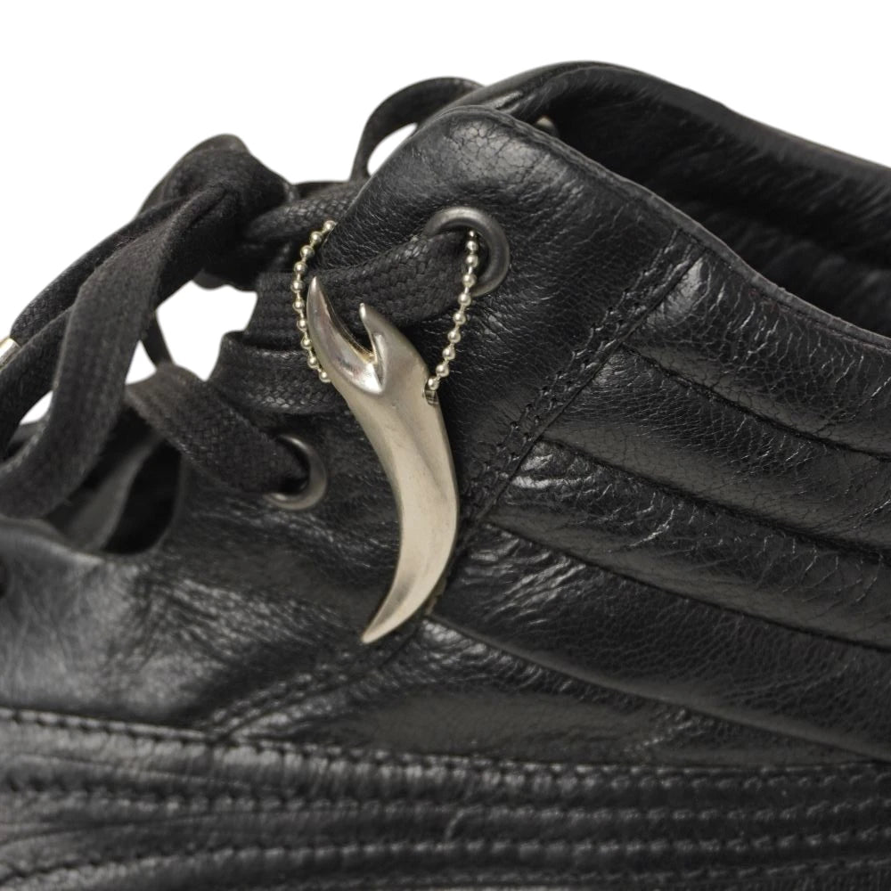 Dettaglio ciondolo metallico originale a forma di artiglio e colletto trapuntato su sneaker Puma x Alexander McQueen