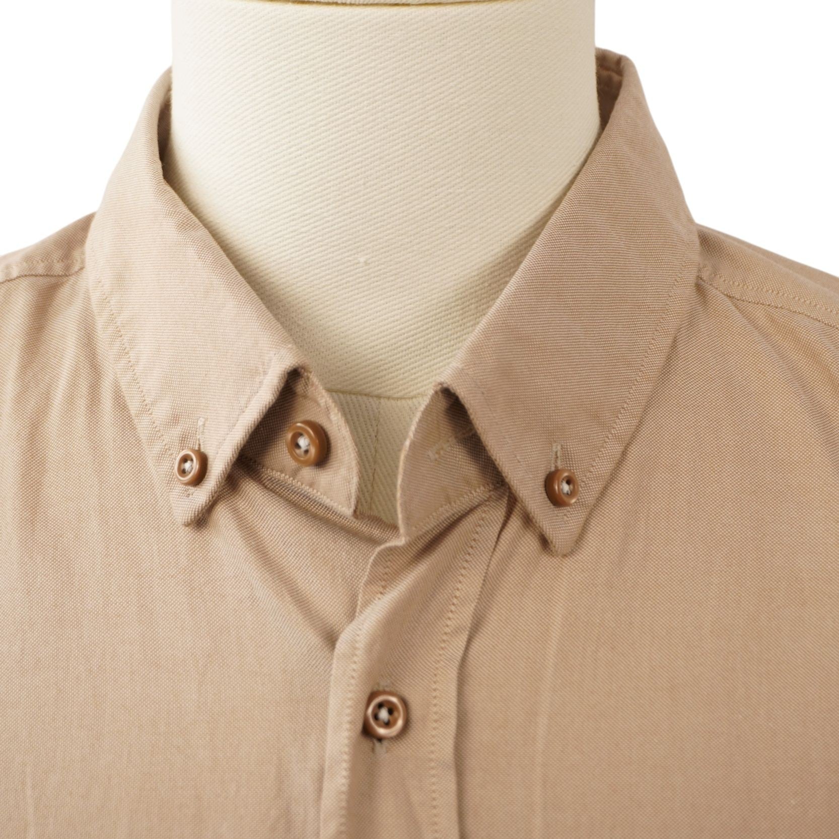 Primo piano del colletto button-down con bottoncini coordinati in tinta della camicia beige BOSS abbottonata sul collo del manichino.