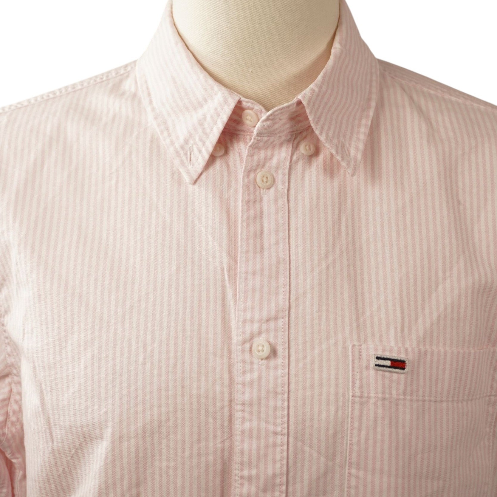  Inquadratura ravvicinata del colletto classico button-down e della chiusura frontale a bottoni chiari.
