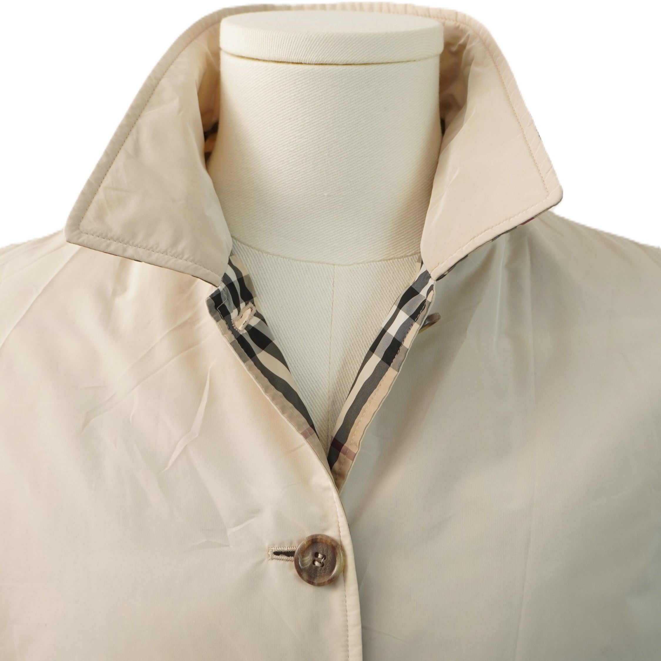 Primo piano del colletto rialzato della giacca Burberry che mostra l'iconica fodera con motivo a quadri Nova Check.