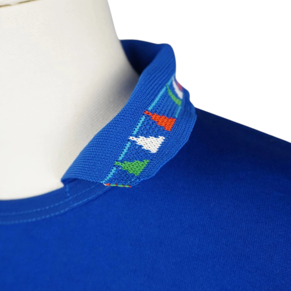 Dettaglio ravvicinato del colletto a polo azzurro con trama geometrica e scudetti tricolore