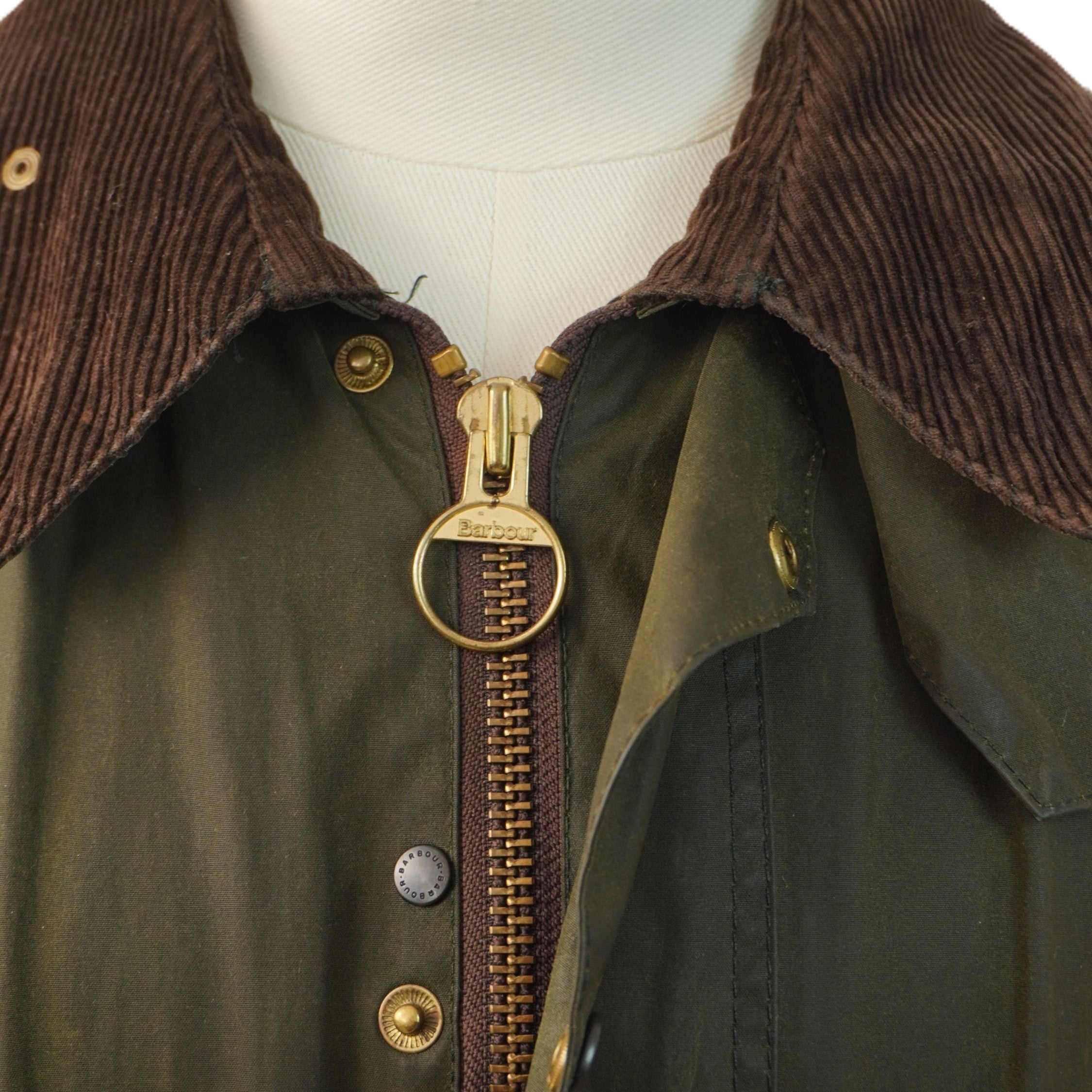 Dettaglio del colletto in velluto a coste marrone e della cerniera metallica dorata con anello originale Barbour.