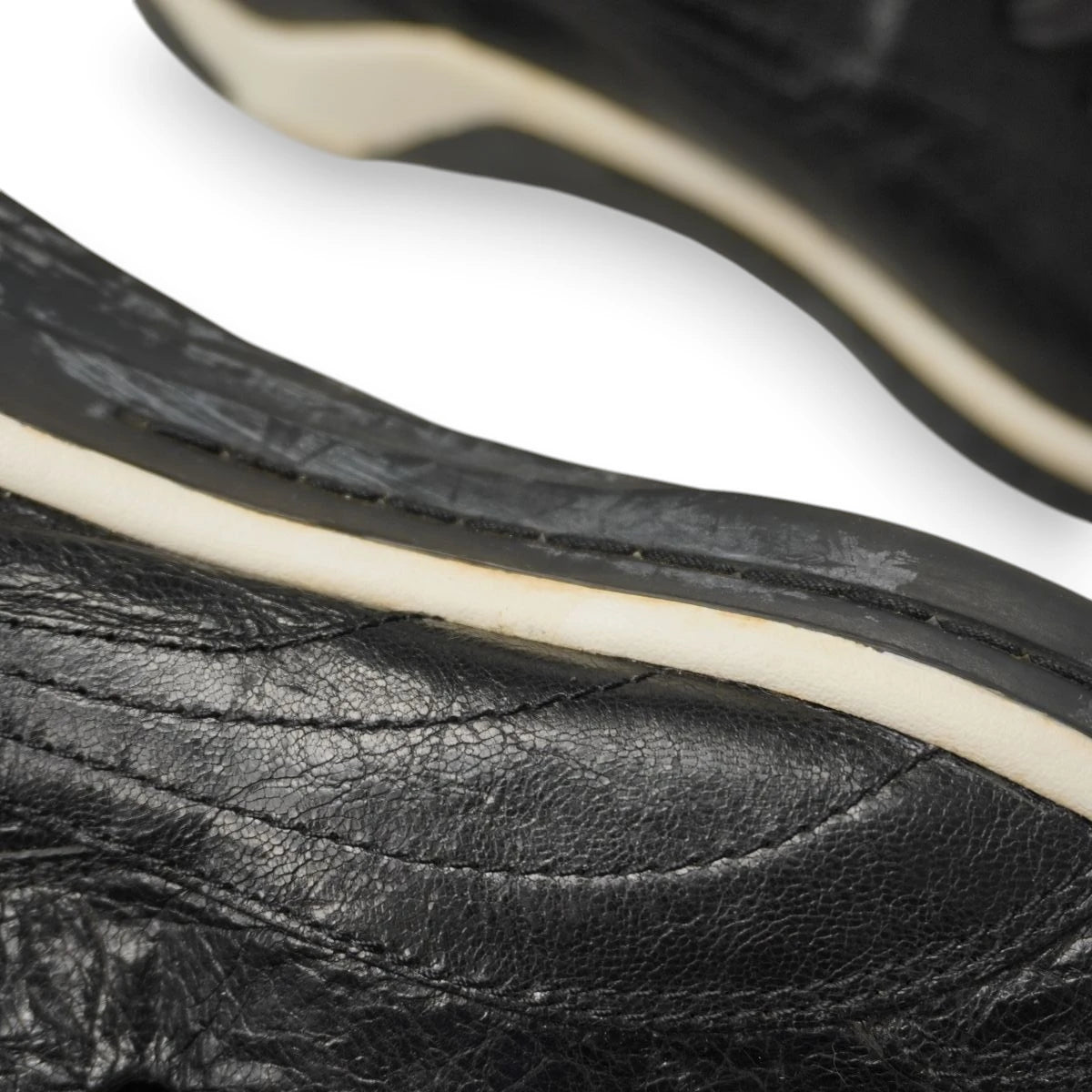 Macro pannello in pelle nera e cucitura perimetrale della suola sneaker Puma x Alexander McQueen