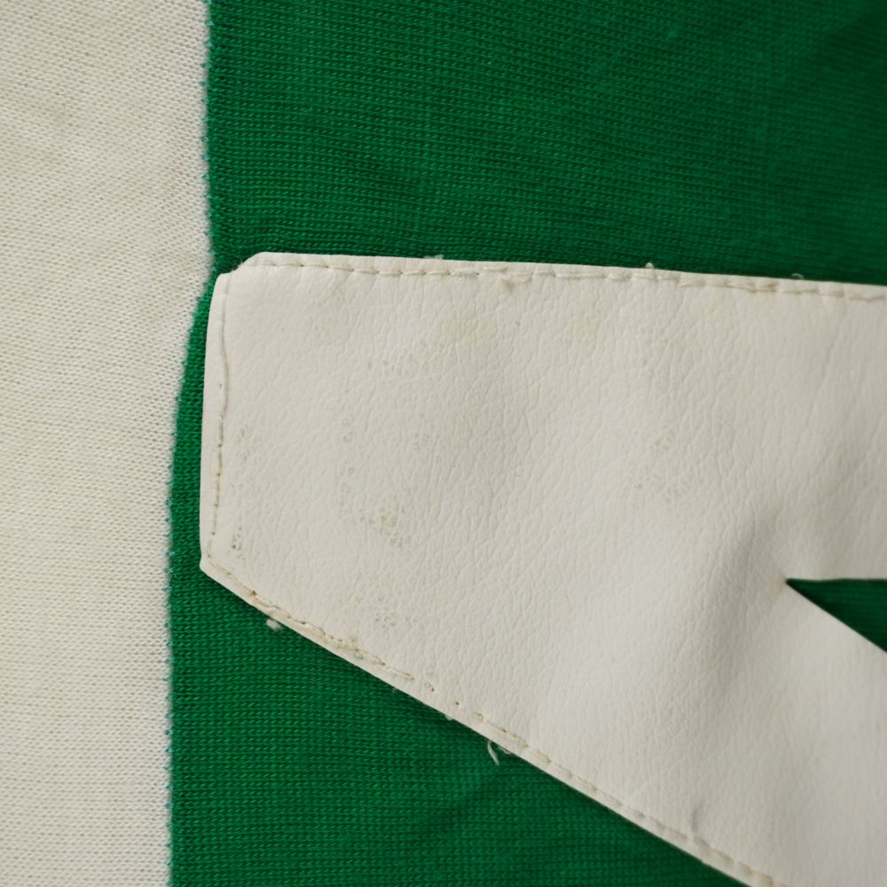Zoom ravvicinato del numero 4 in similpelle bianca con cuciture a macchina su tessuto verde