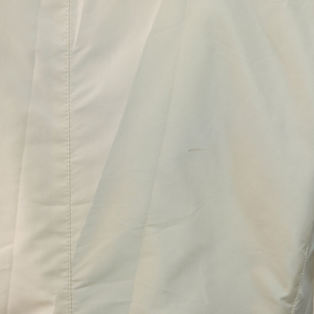 Foto ravvicinata del tessuto beige che mostra l'entità e la dimensione della piccola macchia presente sulla parte alta della schiena.