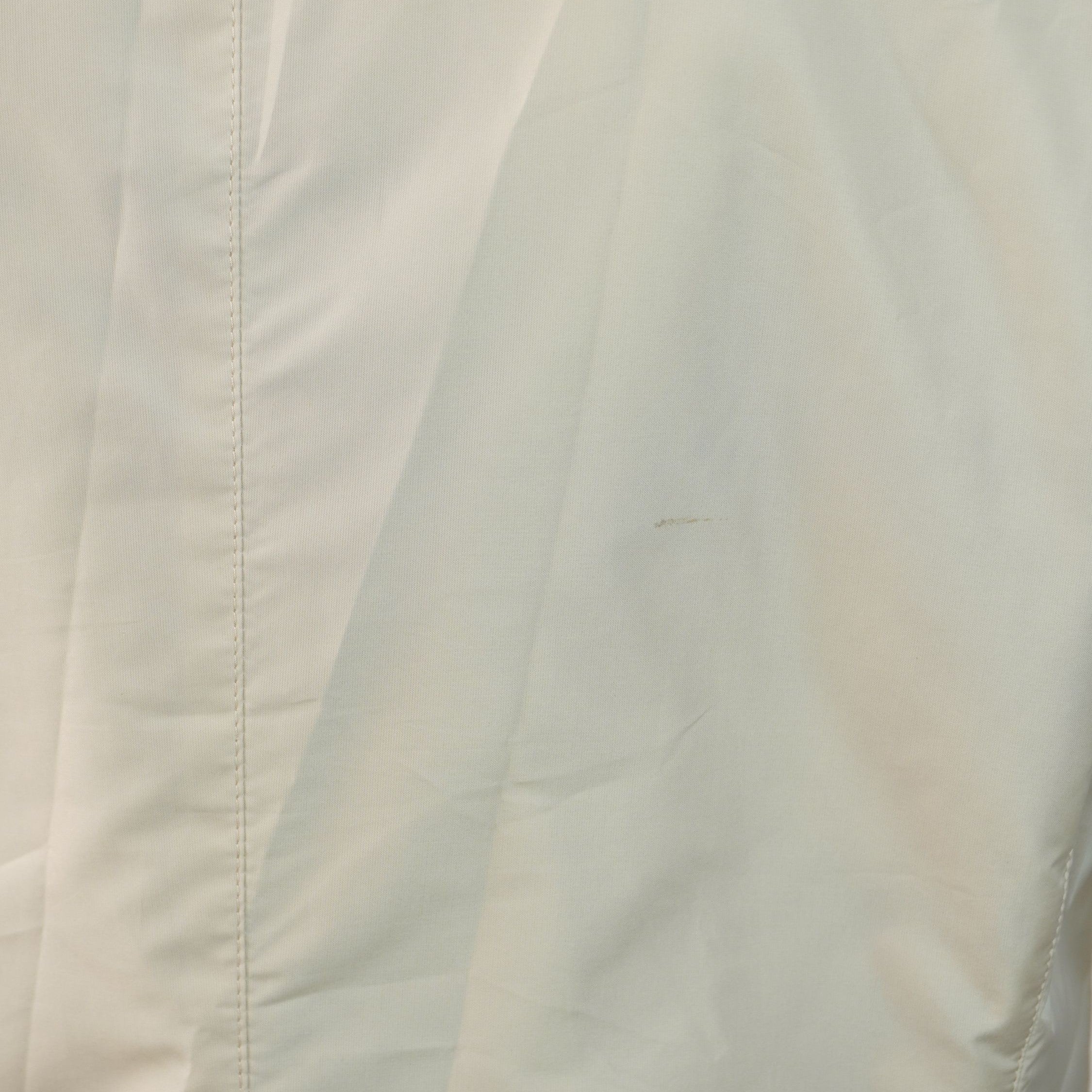 Foto ravvicinata del tessuto beige che mostra l'entità e la dimensione della piccola macchia presente sulla parte alta della schiena.
