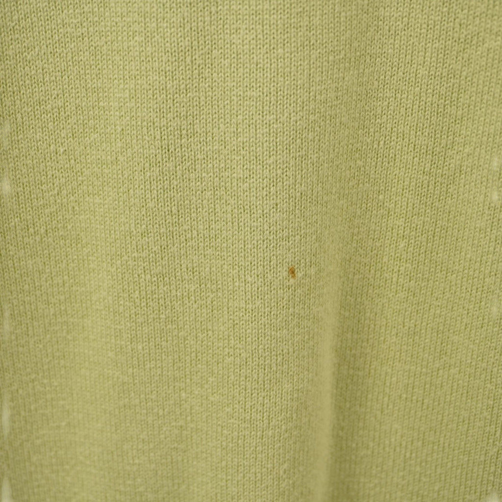 Foto ravvicinata della trama del tessuto verde che mostra il dettaglio di una piccola macchia.