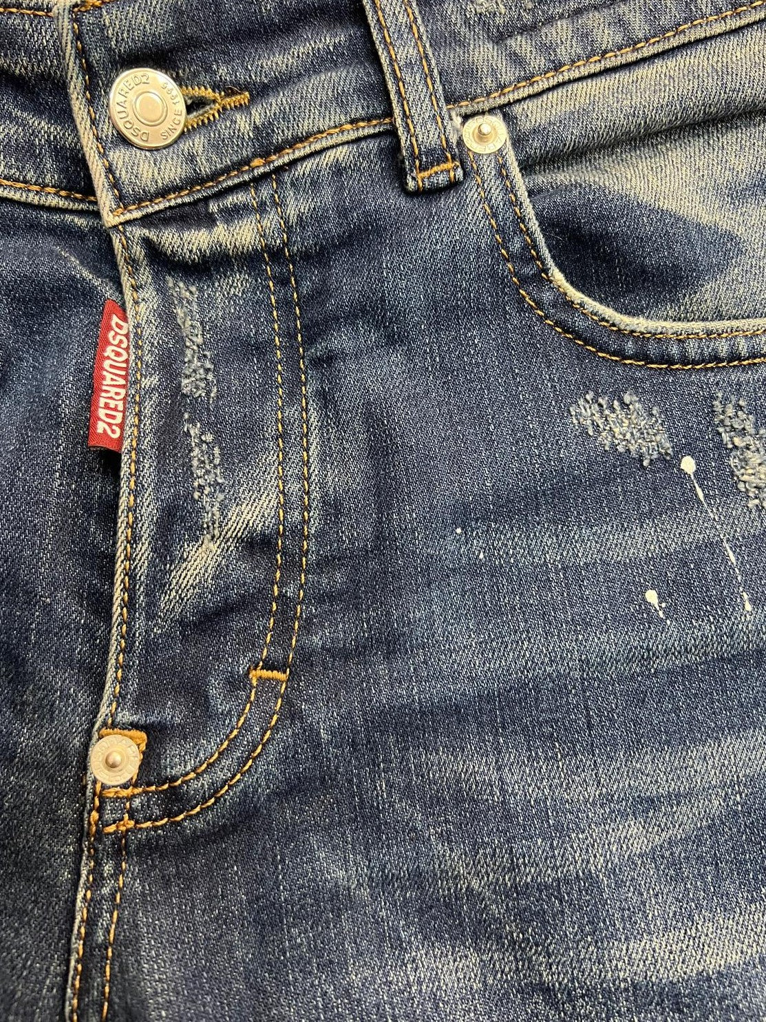 Primo piano della chiusura a bottoni con l'iconica etichetta rossa verticale del brand DSquared2.
