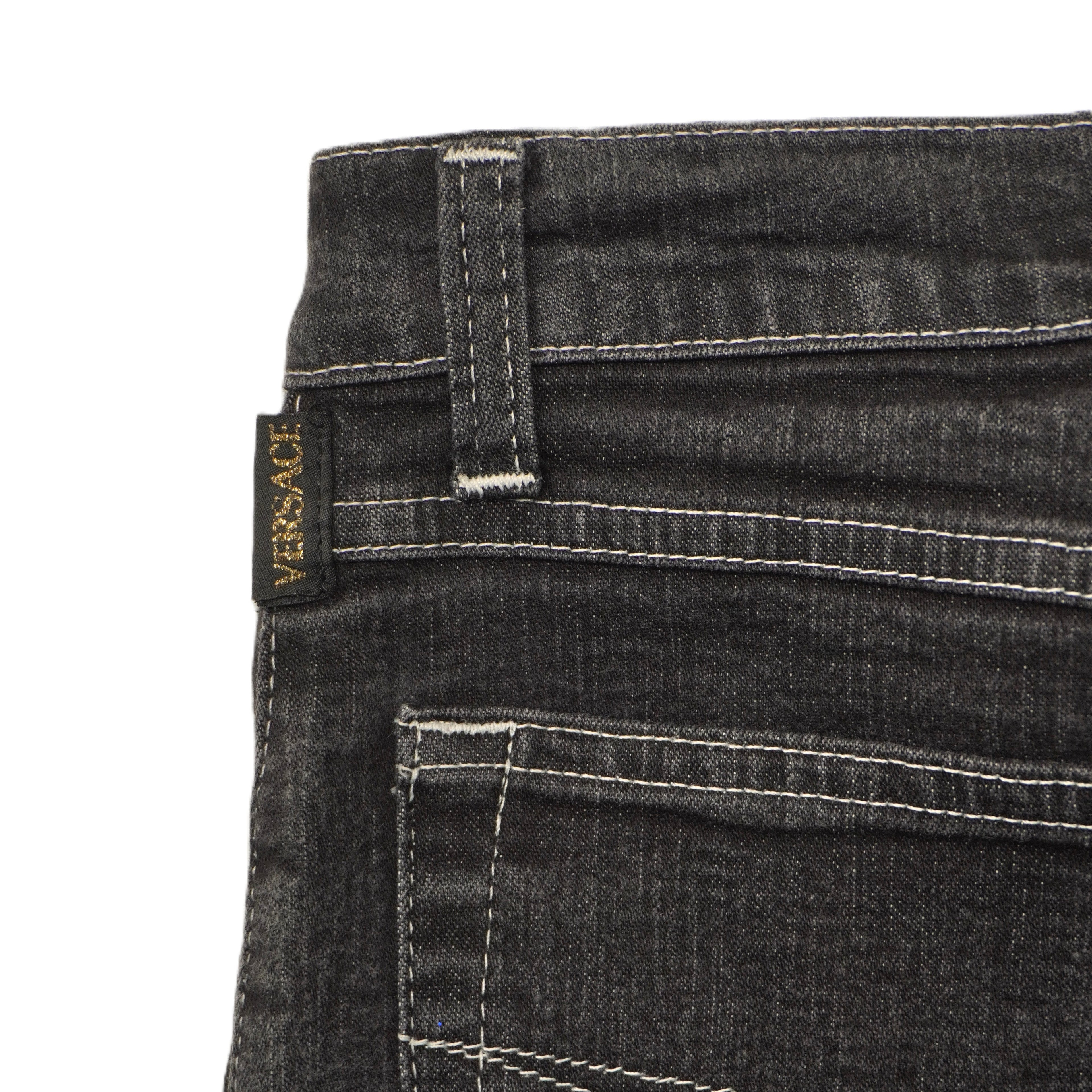 Particolare del fianco superiore dei jeans neri che evidenzia la qualità delle doppie cuciture e dei piccoli rivetti.