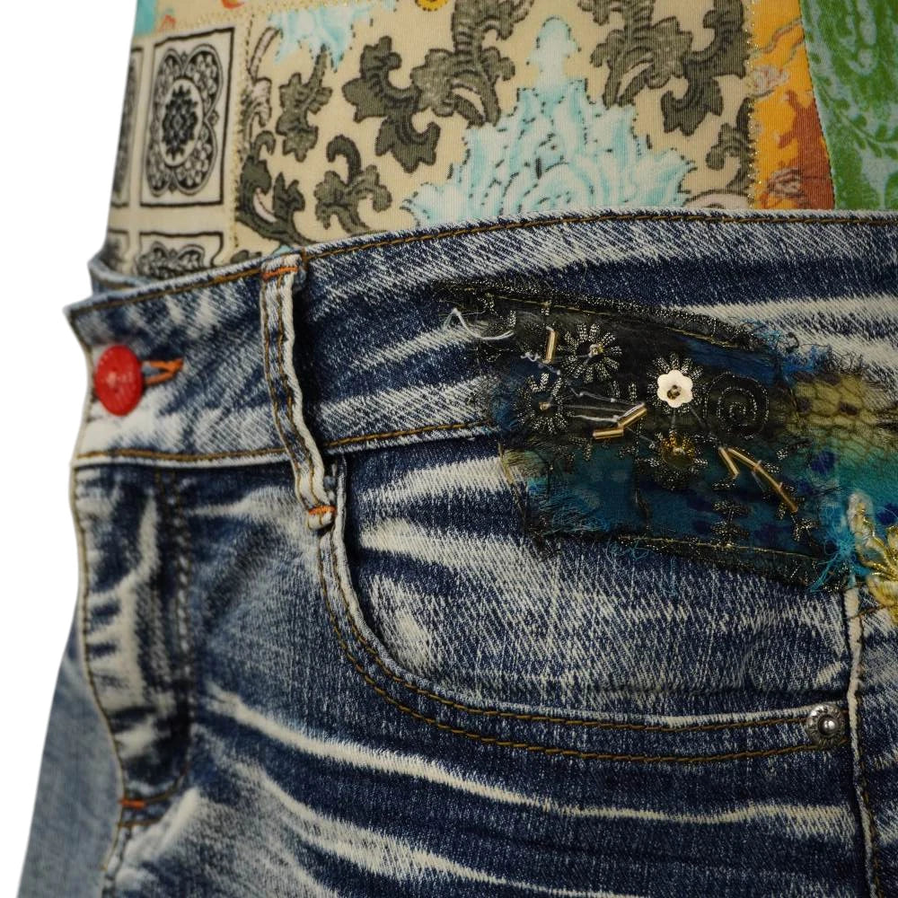 Primo piano del fianco della gonna in jeans con inserto in pizzo nero ricamato di paillettes e perline dorate.