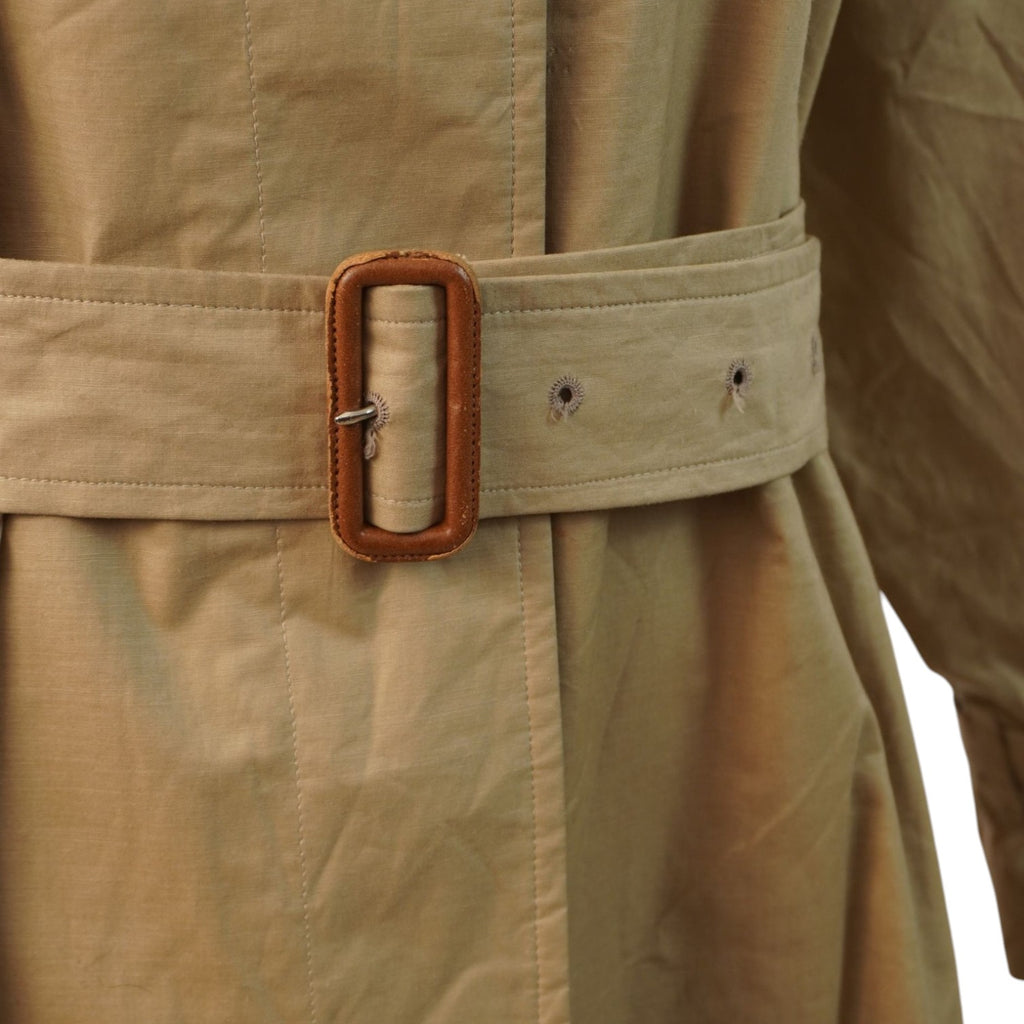 Primo piano della cintura in gabardine di cotone con l'iconica fibbia rettangolare rivestita in pelle marrone.