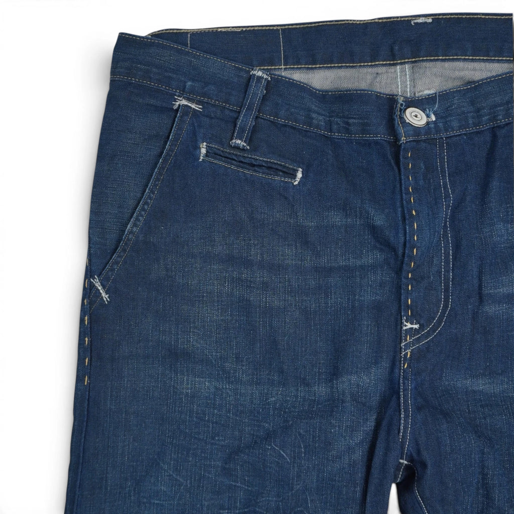 Primo piano frontale destro del girovita dei jeans Levi's con cuciture chiare, passante per cintura e bottone metallico.