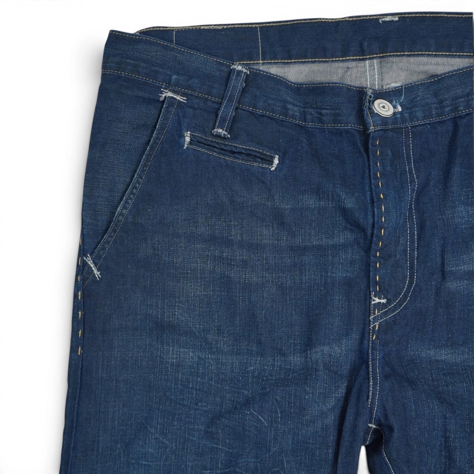 Primo piano frontale destro del girovita dei jeans Levi's con cuciture chiare, passante per cintura e bottone metallico.
