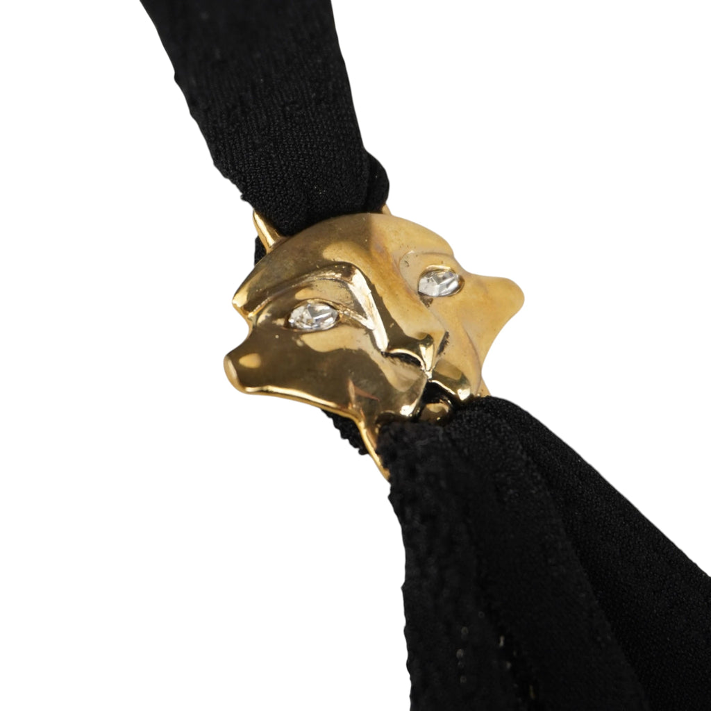 Primo piano del dettaglio metallico dorato a forma di testa di pantera con strass incastonati negli occhi.