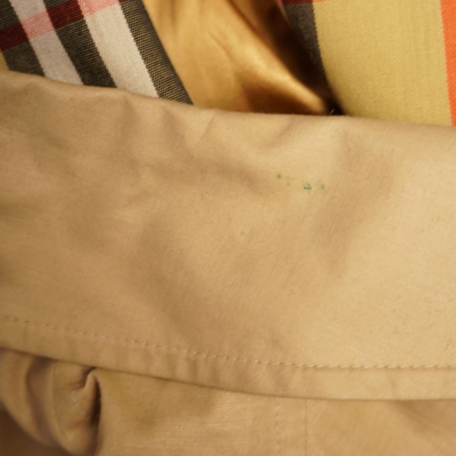 Macro su una piccola macchia pigmentata verde e blu sulla gabardine di cotone miele inserita per trasparenza.
