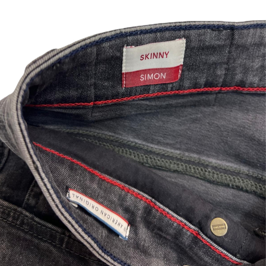 Primo piano dell'interno della parte superiore dei jeans, che mostra la fodera della tasca e la fettuccia con i colori iconici del brand.