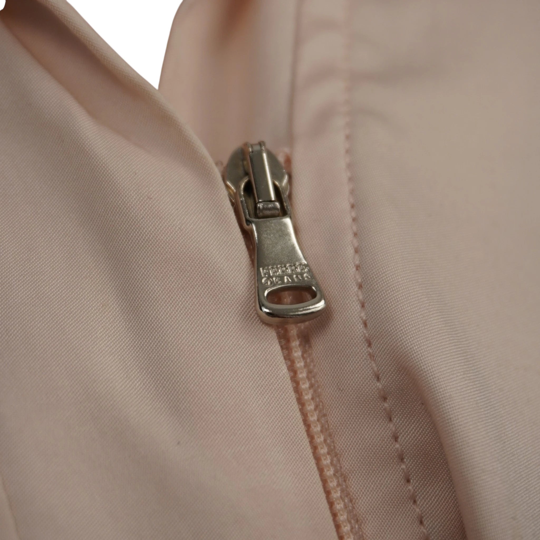 Primo piano della chiusura lampo metallica color argento della giacca del tailleur rosa cipria.