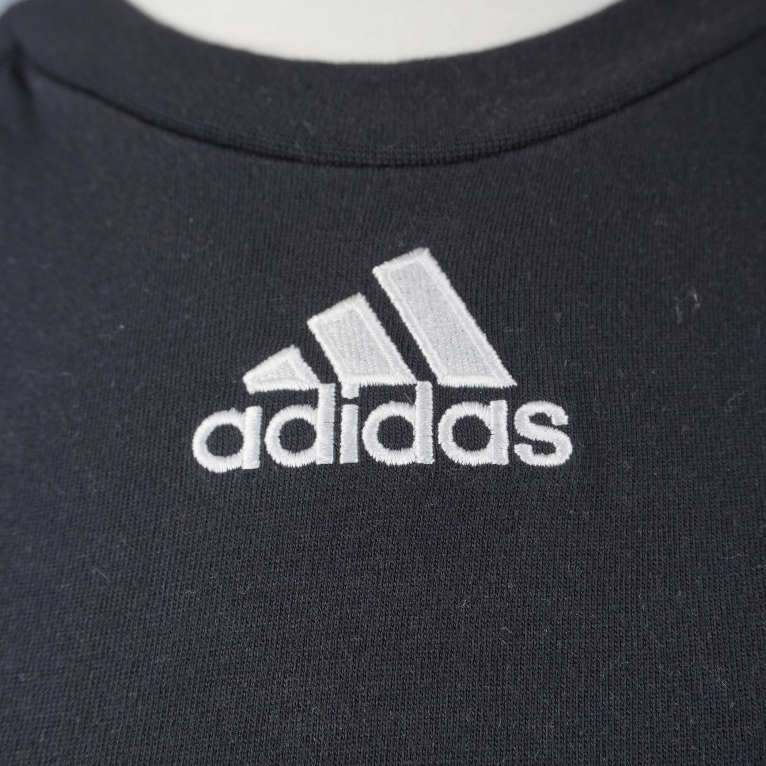 Primo piano del logo Adidas originale vintage degli anni 90 ricamato in bianco sul petto della maglia da allenamento DFB.