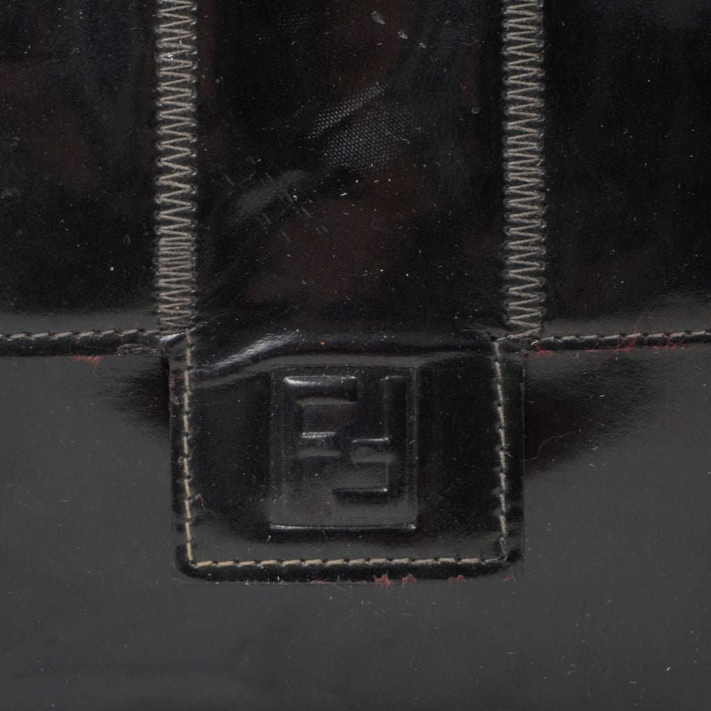 Primo piano del logo iconico FF di Fendi impresso a rilievo sulla patta frontale della borsa in pelle lucida.