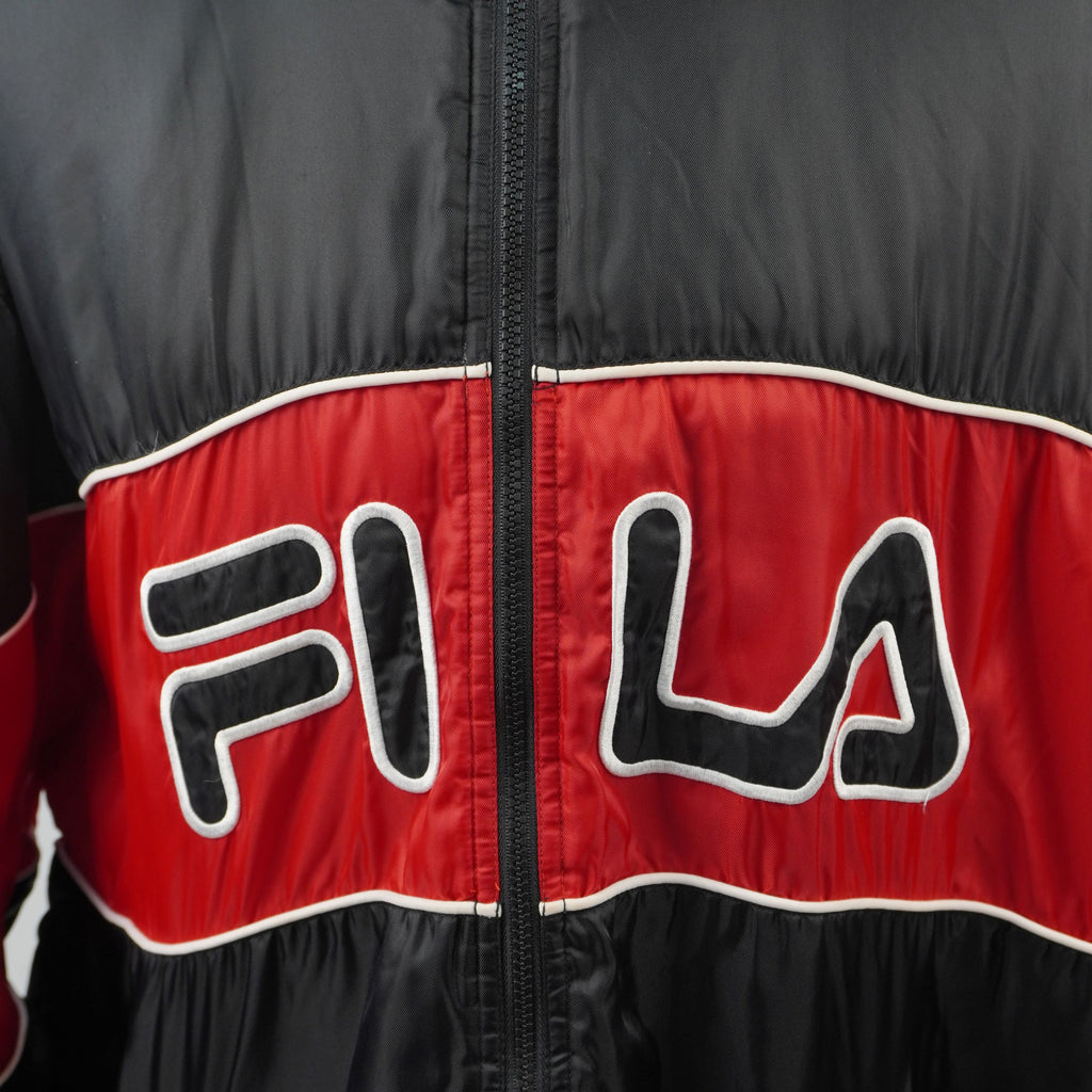  Primo piano del maxi logo Fila ricamato con profili bianchi a contrasto sulla banda rossa frontale della giacca.
