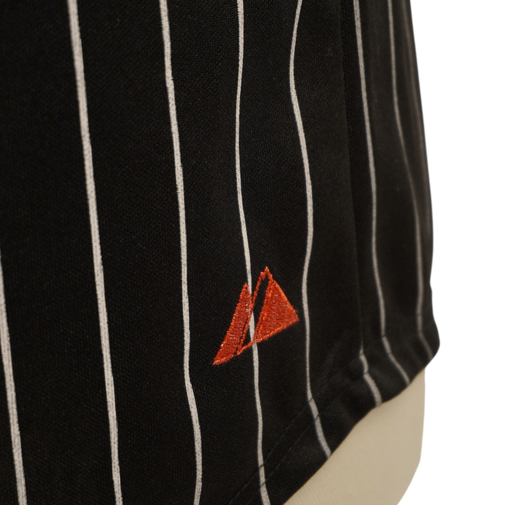 Ingrandimento del logo Majestic ricamato in rosso sulle righe gessate della maglia.