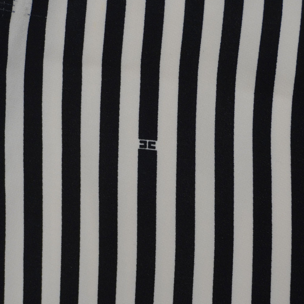 Primo piano del pattern optical a righe con piccolo logo monogram Elisabetta Franchi ricamato tono su tono.