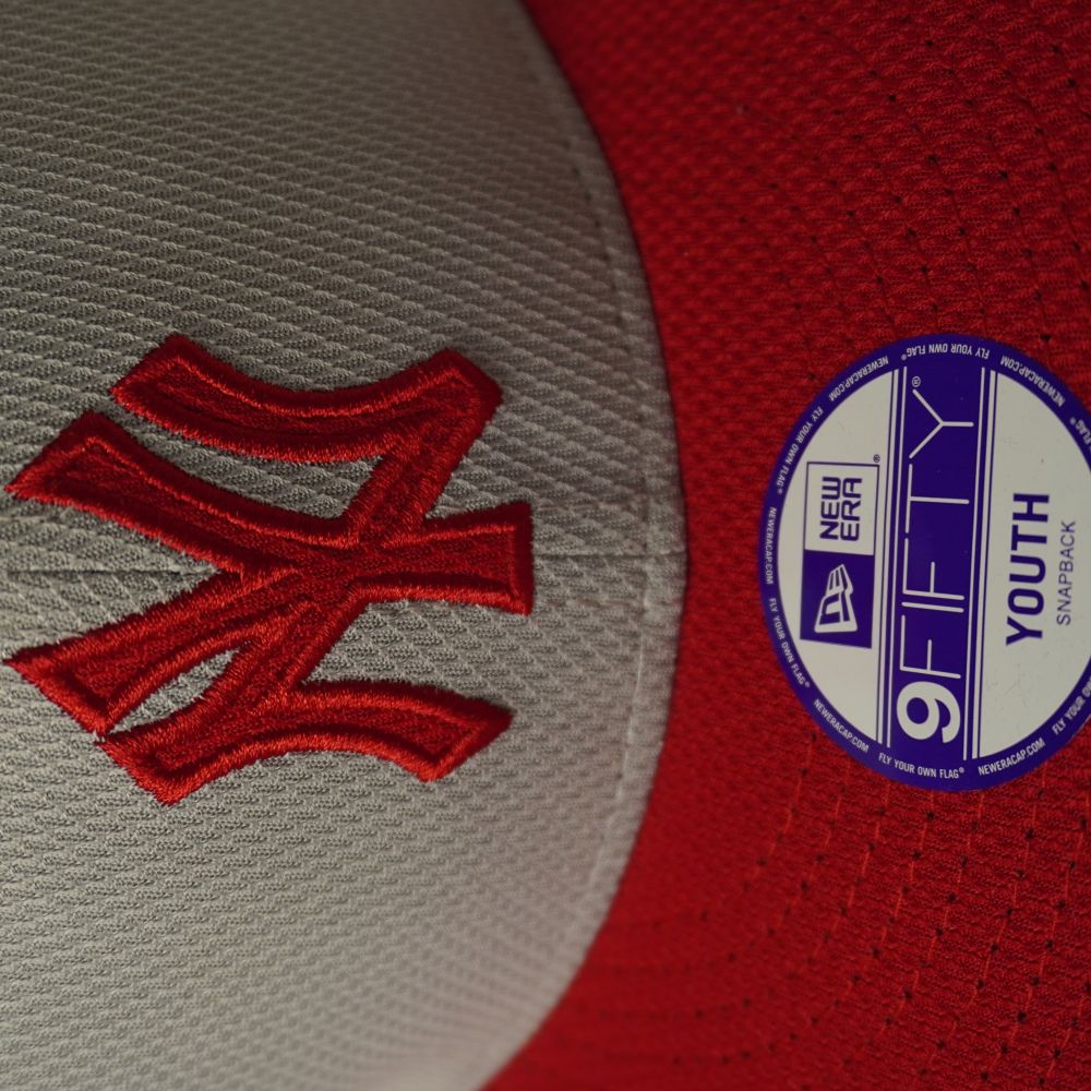 Primo piano del logo New York Yankees ricamato in rosso a rilievo e del bollino adesivo originale tondo New Era 9FIFTY Youth.