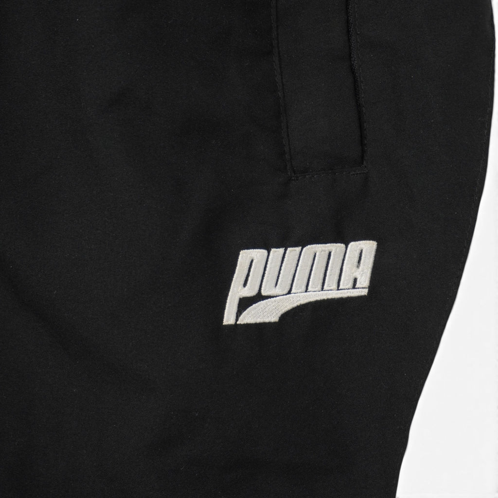 Dettaglio macro logo vintage Puma ricamato in filo bianco su tessuto woven nero
