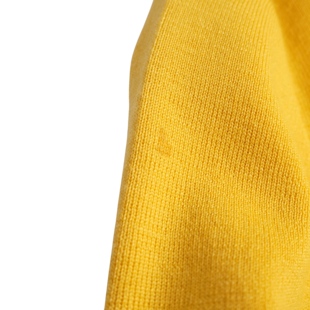  Primo piano del tessuto in lana giallo che mostra la piccola macchia sul lato superiore della manica sinistra per trasparenza usato.