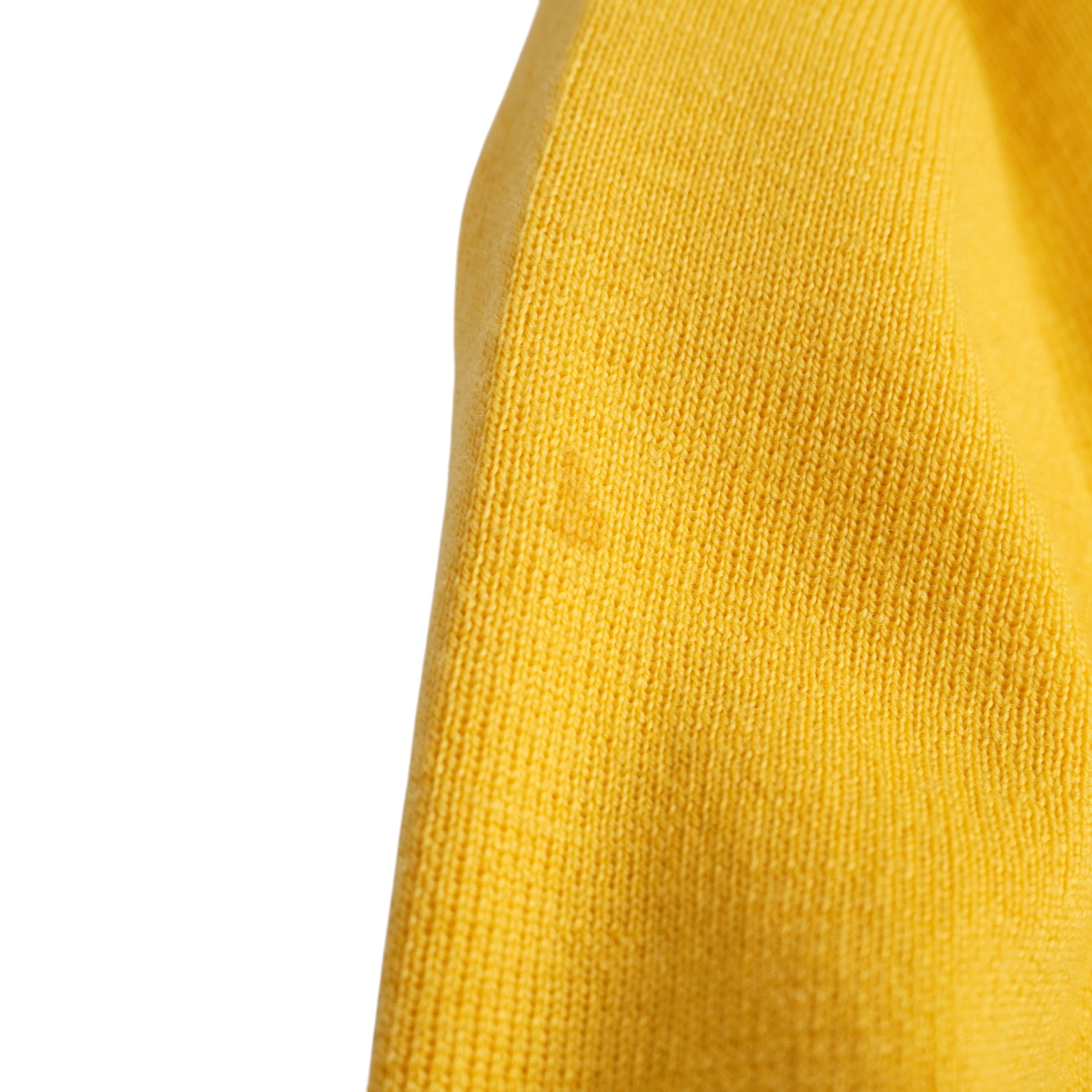  Primo piano del tessuto in lana giallo che mostra la piccola macchia sul lato superiore della manica sinistra per trasparenza usato.
