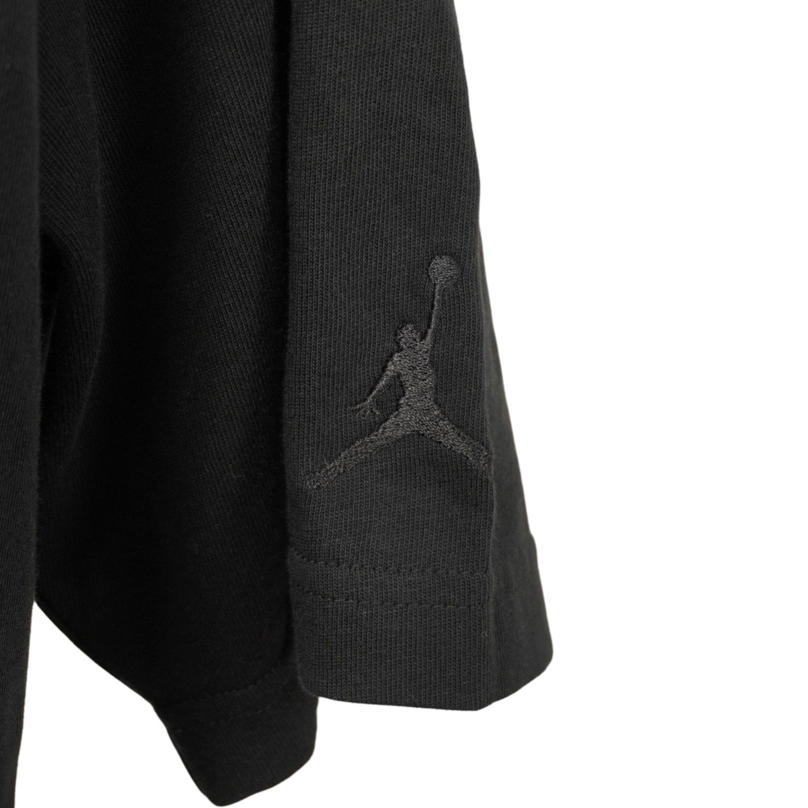 Dettaglio del logo Jumpman termosaldato tono su tono sulla manica della T-shirt.