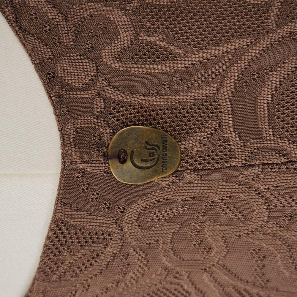 Dettaglio del medaglione circolare in ottone brunito con logo inciso Class Roberto Cavalli sul retro dell'abito.