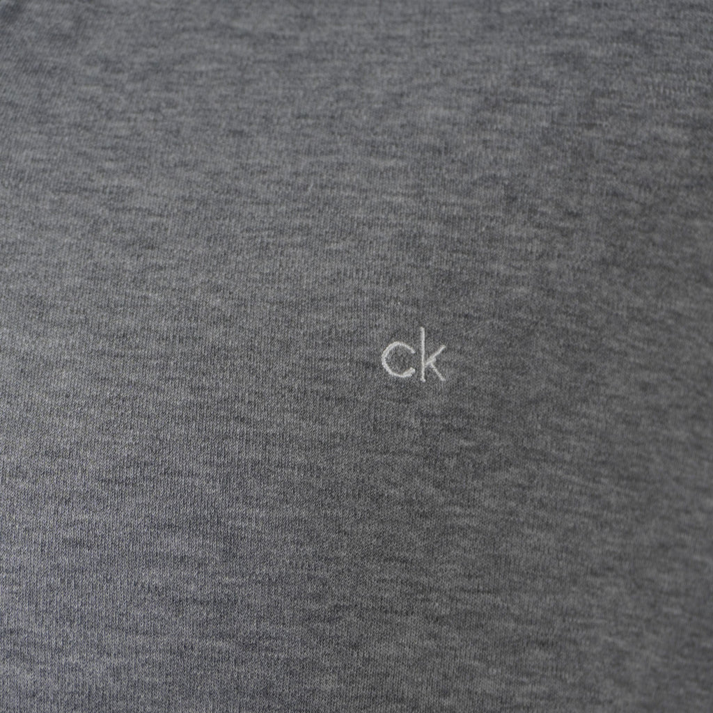 Primo piano ravvicinato del micro ricamo del logo ck sul petto della polo grigia Calvin Klein