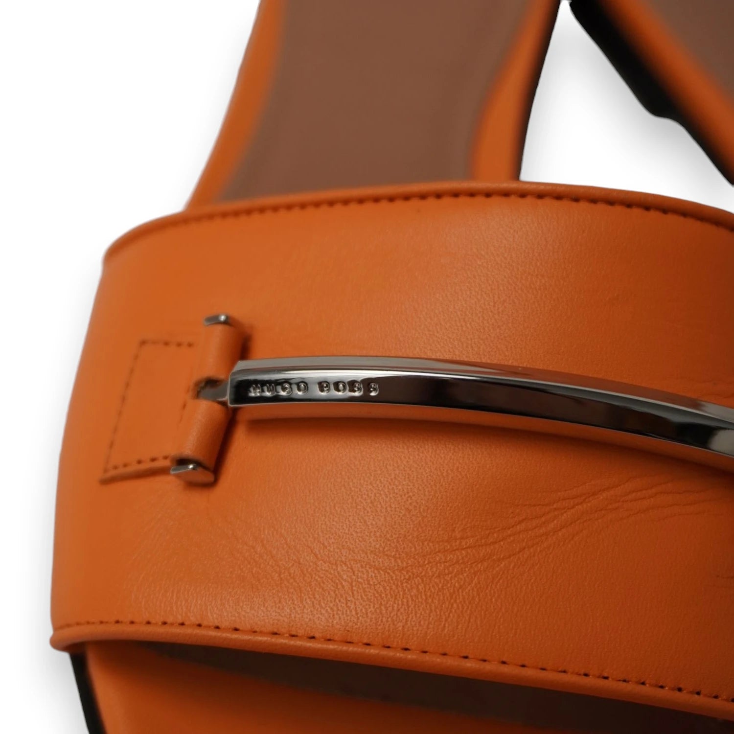 Dettaglio ravvicinato del morsetto metallico cromato con logo inciso sui sandali BOSS.