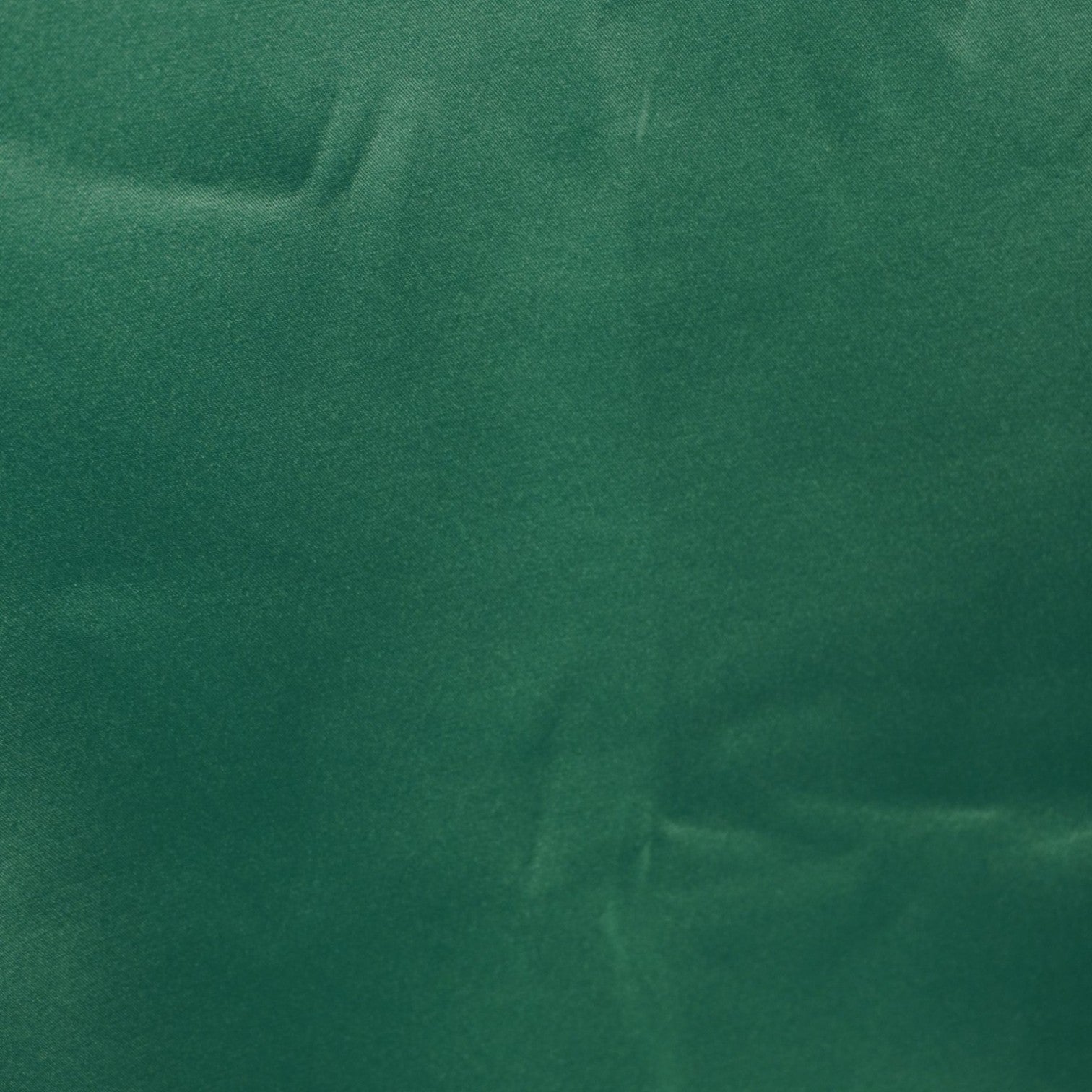 Primo piano della parte inferiore posteriore del vestito verde che mostra la finitura dell'orlo e le impercettibili striature menzionate.