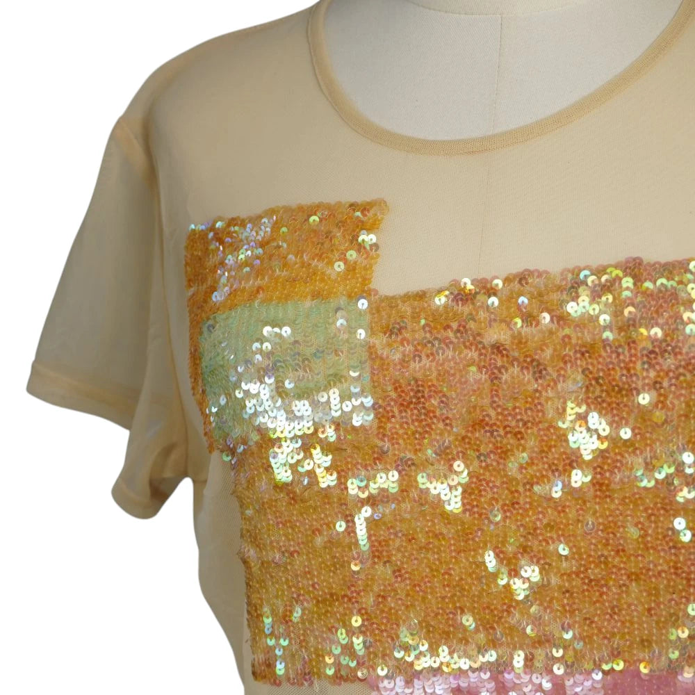 Primo piano del ricamo frontale geometrico asimmetrico con paillettes fitte e iridescenti nei toni del rosa e dell'arancione.