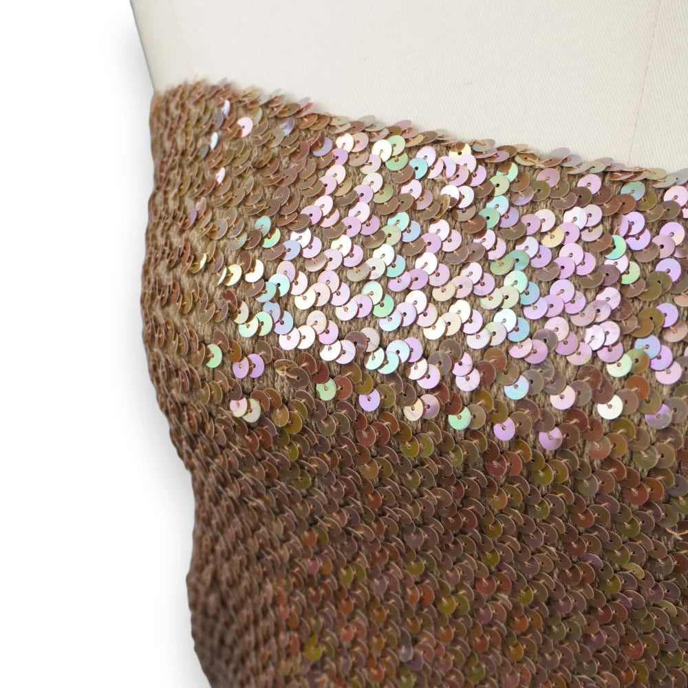 Primo piano ravvicinato delle paillettes con finitura olografica che riflettono sfumature pastello lilla, rosa e verdi.