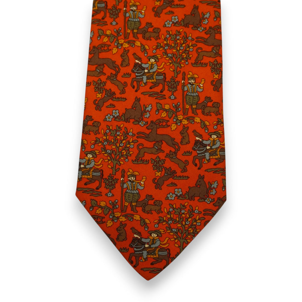 Primo piano frontale della pala della cravatta Etro arancione che mostra la simmetria del taglio sartoriale e la stampa con cavalieri.
