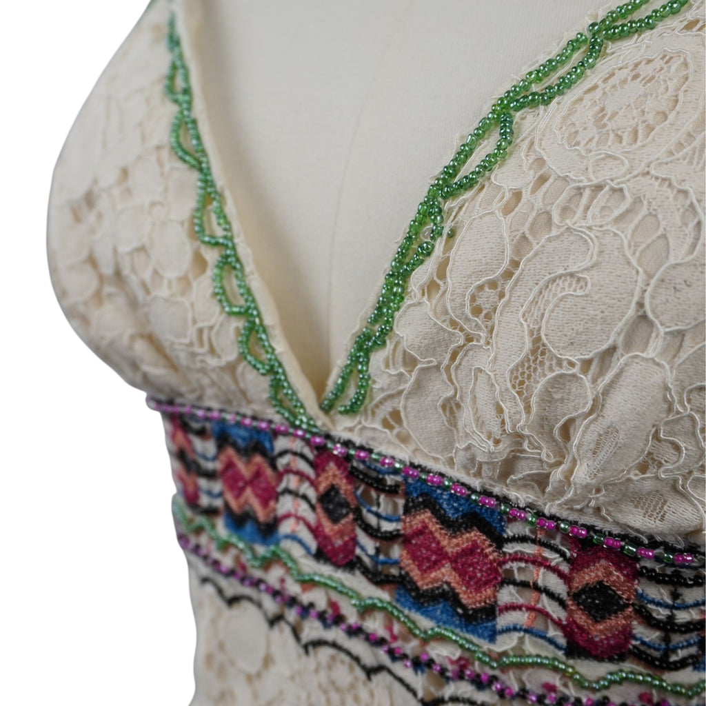 Macro dello scollo a V profilato con micro perline verdi e della fascia ricamata in lurex multicolore