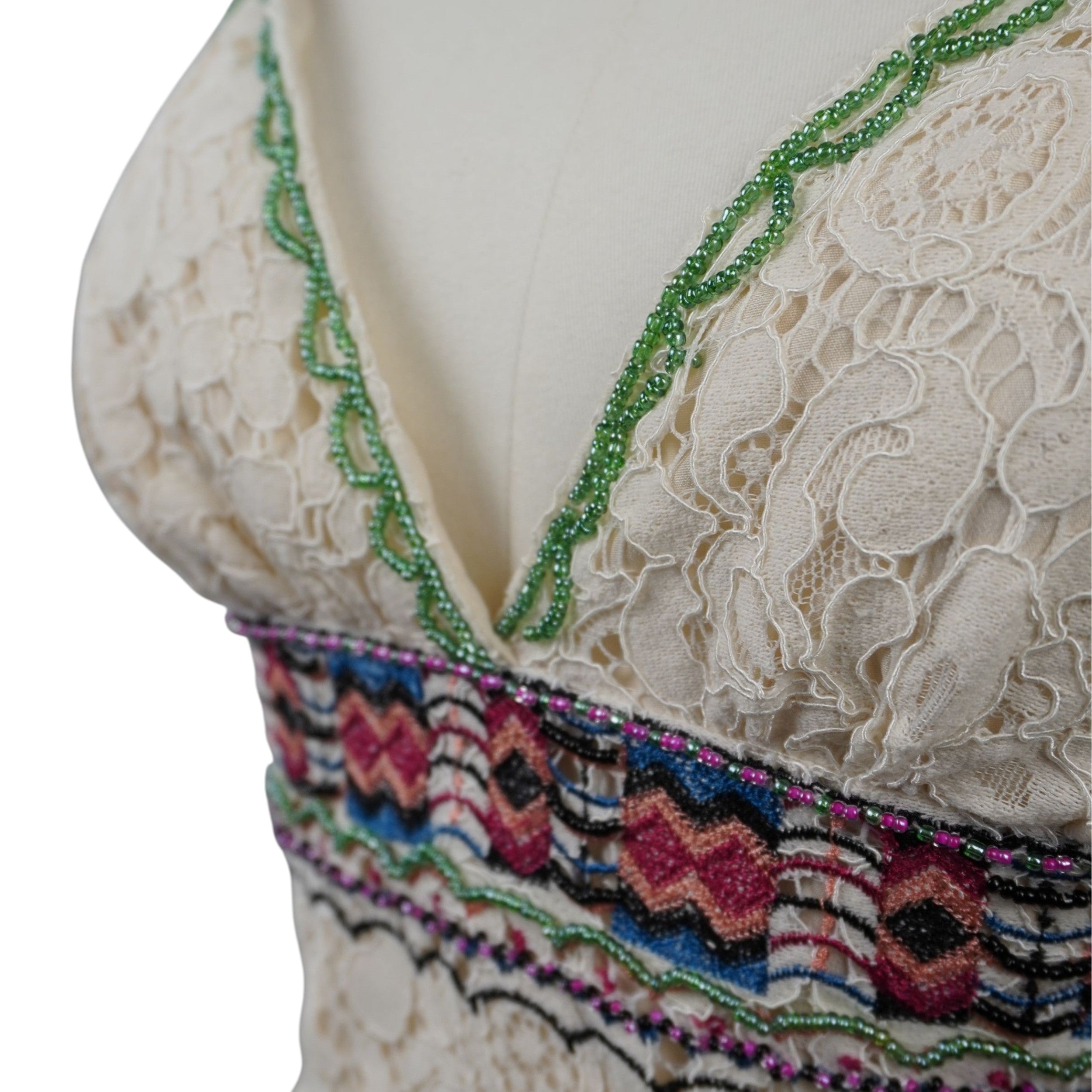 Macro dello scollo a V profilato con micro perline verdi e della fascia ricamata in lurex multicolore
