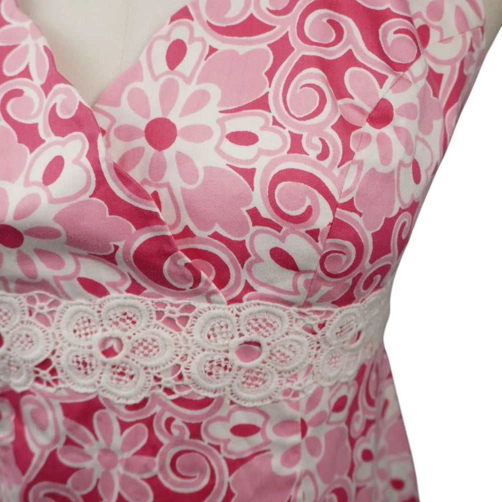 Primo piano della spessa fascia in pizzo macramè bianco ricamato a traforo posizionato sottoseno sulla camicetta rosa Luisa Spagnoli.