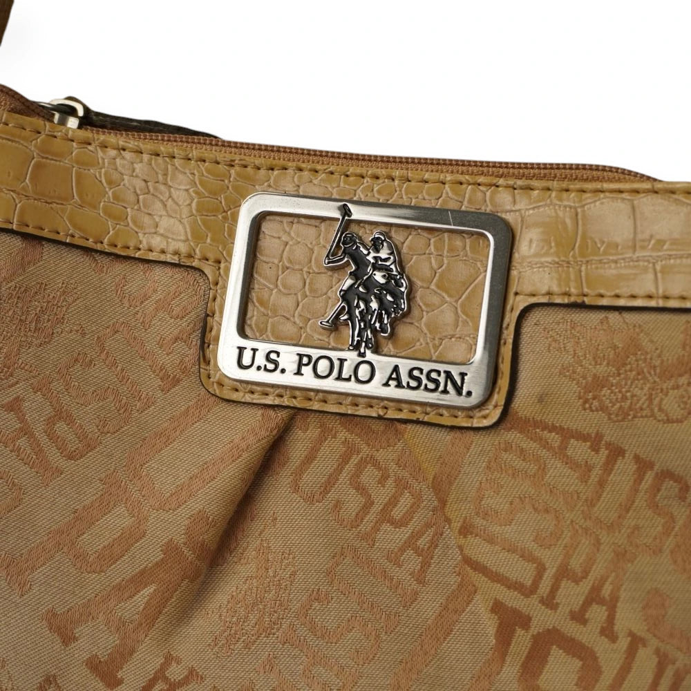 Primo piano della placca rettangolare in metallo con il logo ufficiale U.S. Polo Assn. sulla texture effetto coccodrillo.