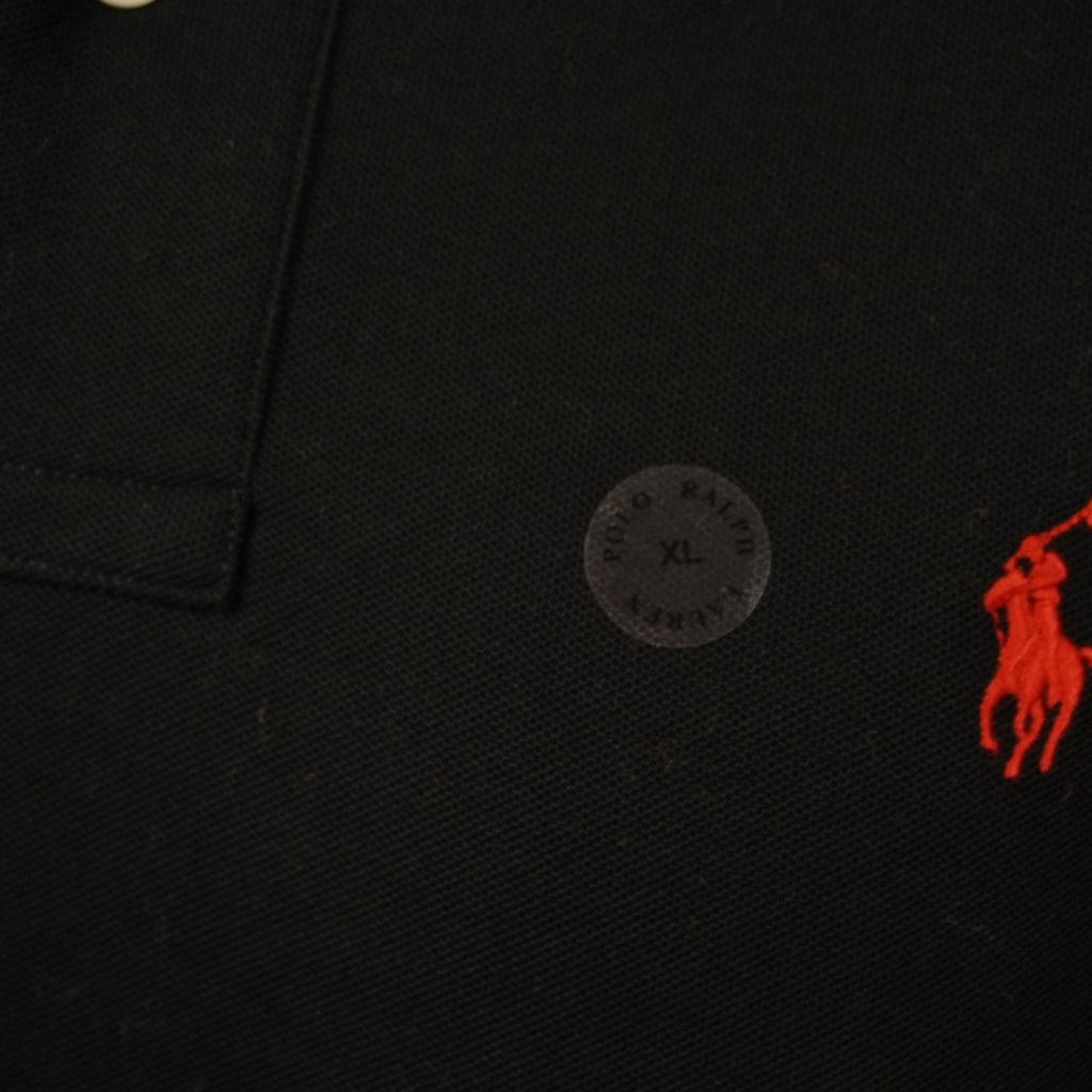 Primo piano del celebre logo del pony rosso ricamato sul tessuto piqué nero.