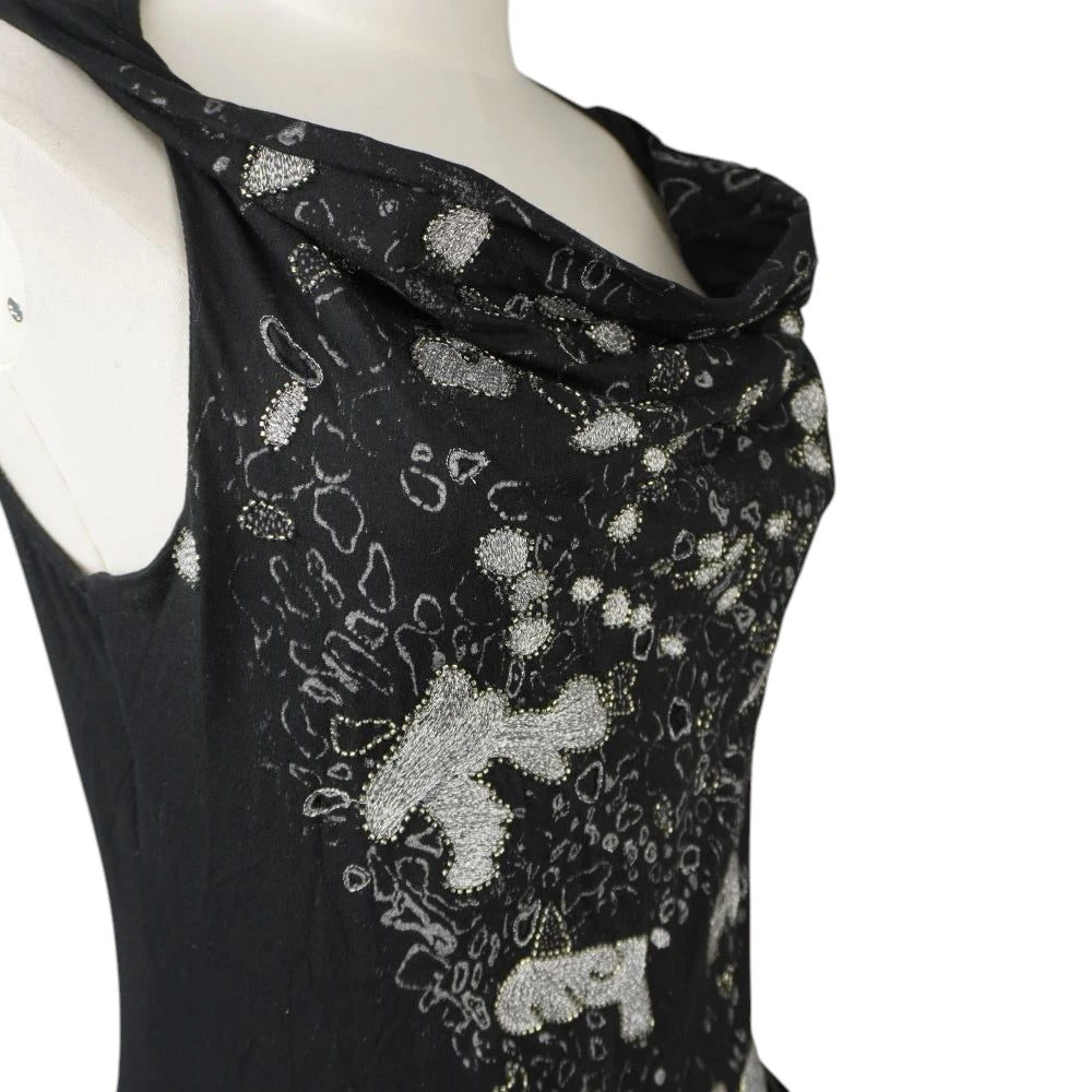Dettaglio ravvicinato dello scollo a cappuccio drappeggiato e della texture dei ricami metallici.